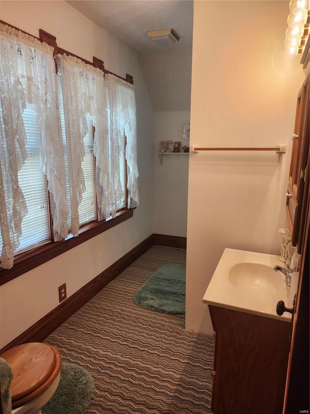 bathroom with vanity, toilet, and vaulted ceiling