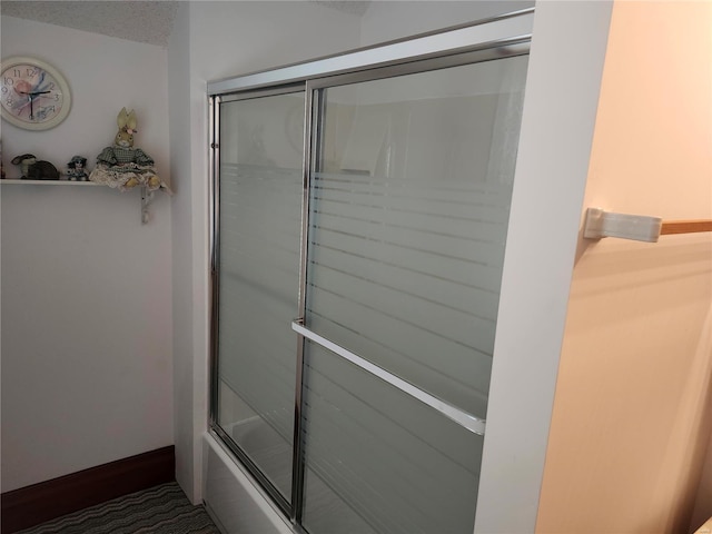 bathroom featuring a textured ceiling and enclosed tub / shower combo