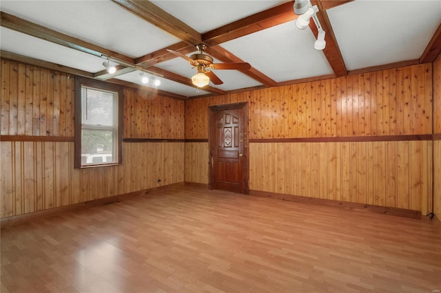 unfurnished room featuring wood-type flooring, wooden walls, and ceiling fan