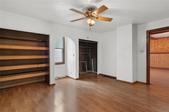 interior space featuring wood walls, ceiling fan, and hardwood / wood-style flooring