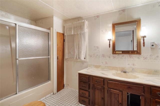 bathroom featuring tile walls, vanity, and bath / shower combo with glass door