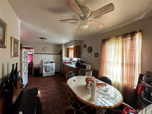 dining space featuring ceiling fan, sink, and dark parquet flooring