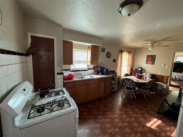 kitchen featuring white range with gas stovetop, sink, parquet flooring, a textured ceiling, and ceiling fan