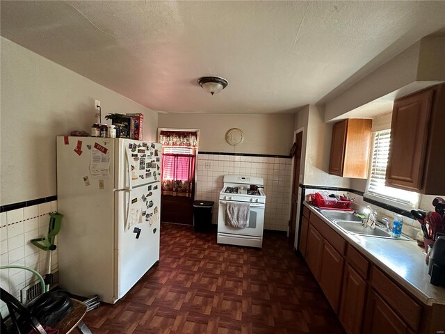 kitchen featuring sink, white appliances, dark parquet floors, a textured ceiling, and tile walls