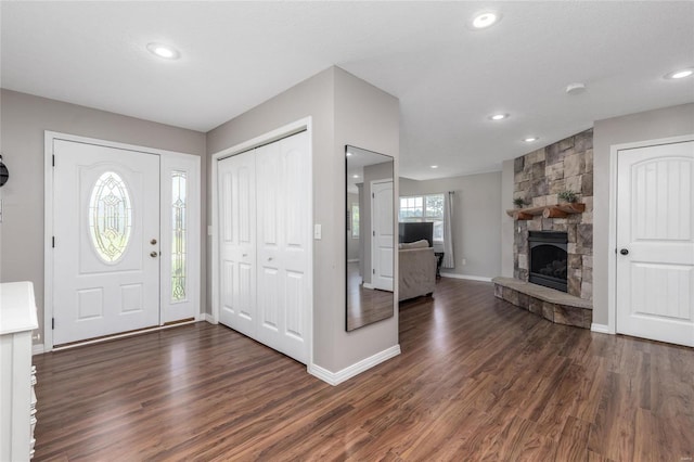 entryway featuring dark wood-type flooring and a stone fireplace