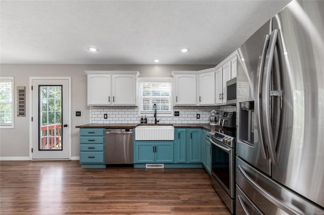 kitchen featuring sink, stainless steel appliances, white cabinetry, and dark hardwood / wood-style flooring