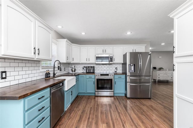 kitchen with appliances with stainless steel finishes, dark wood-type flooring, tasteful backsplash, blue cabinetry, and white cabinets