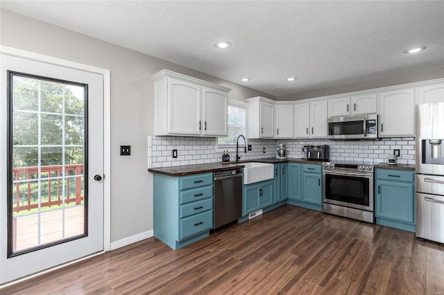 kitchen featuring blue cabinets, appliances with stainless steel finishes, dark hardwood / wood-style floors, and a healthy amount of sunlight