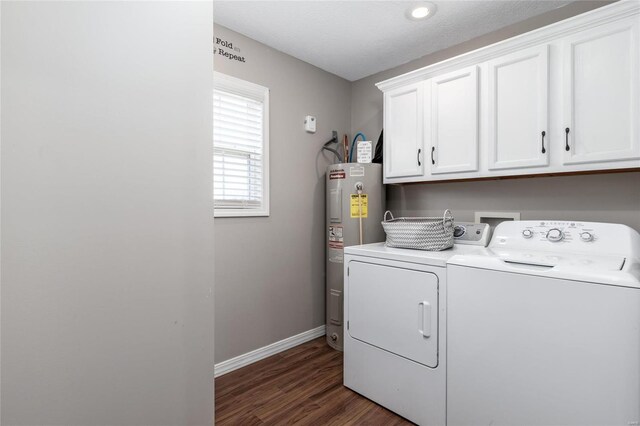 washroom featuring dark wood-type flooring, washing machine and clothes dryer, electric water heater, and cabinets