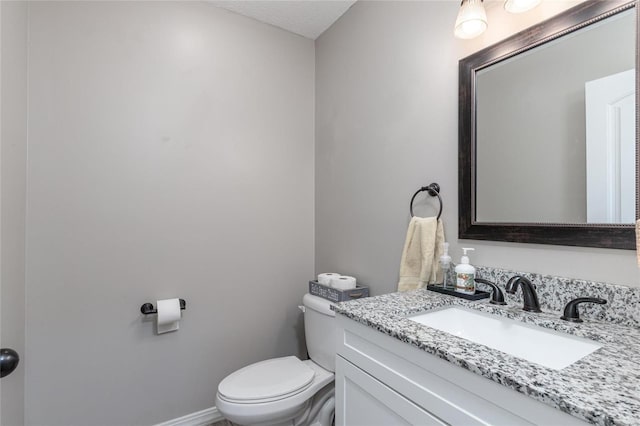 bathroom featuring a textured ceiling, vanity, and toilet