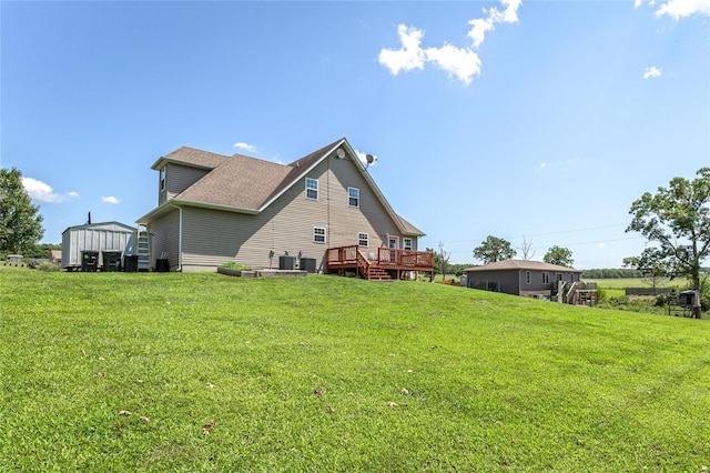 rear view of property featuring a deck, an outbuilding, and a lawn