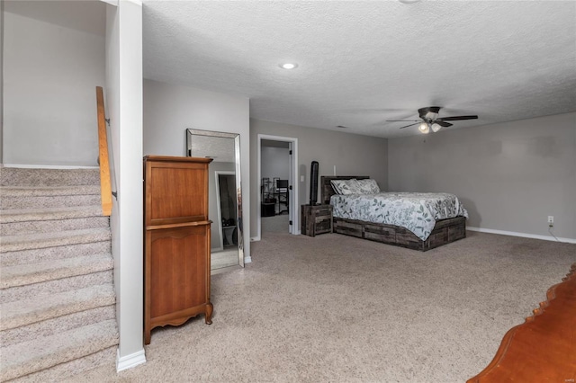 bedroom with ceiling fan, light colored carpet, and a textured ceiling