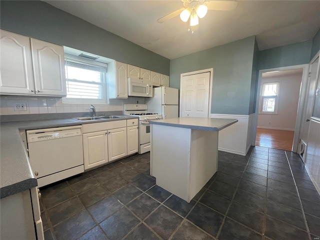 kitchen with white appliances, white cabinetry, a healthy amount of sunlight, and sink