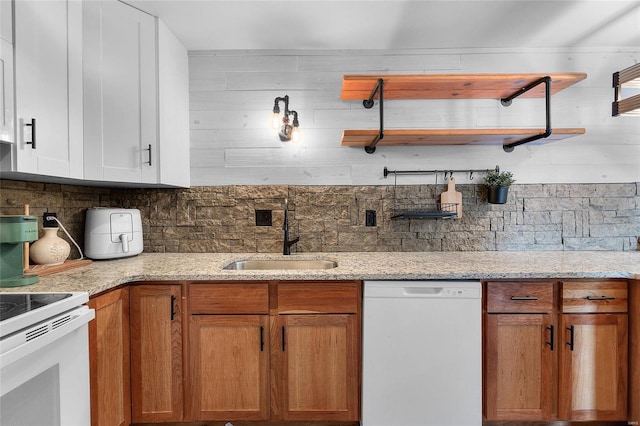 kitchen with dishwasher, light stone counters, sink, and backsplash