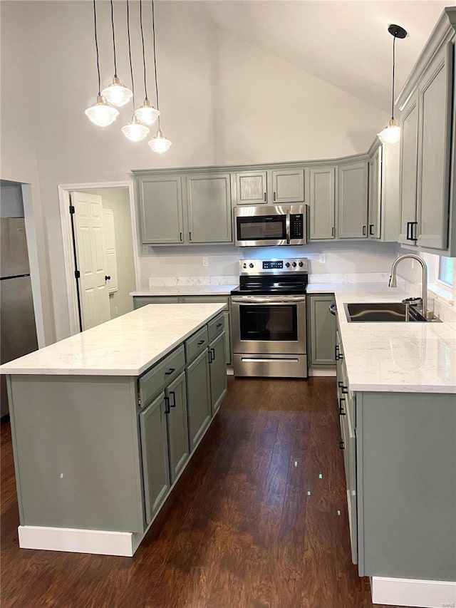 kitchen featuring appliances with stainless steel finishes, a center island, hanging light fixtures, and sink