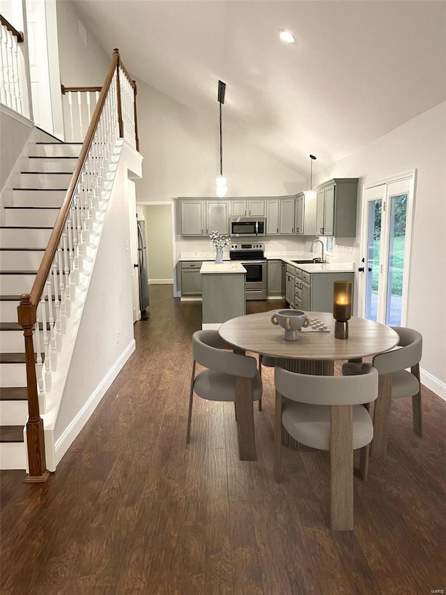 dining room with sink, dark wood-type flooring, and high vaulted ceiling