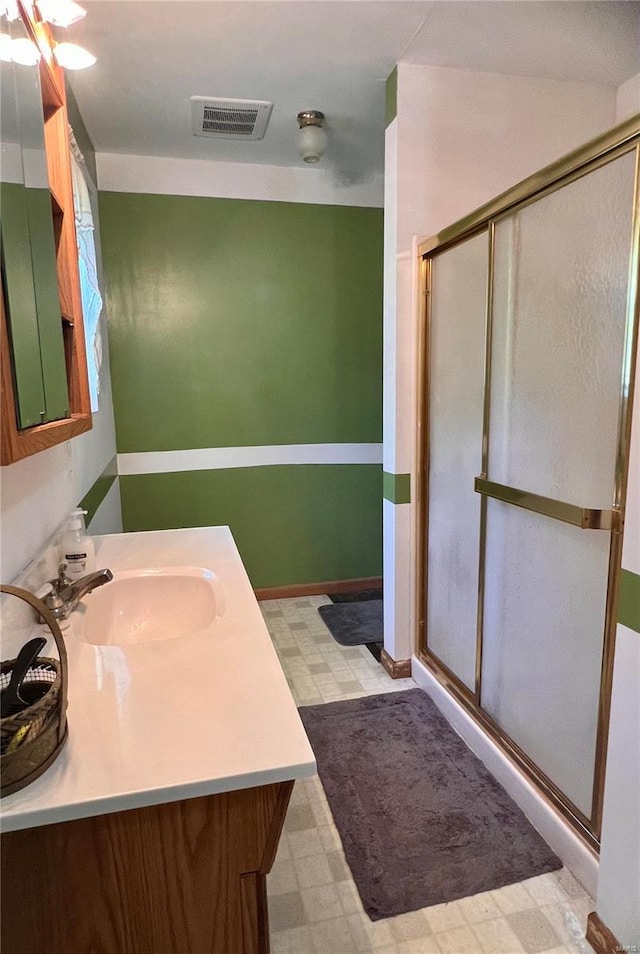 bathroom with tile patterned flooring, a shower with door, and vanity