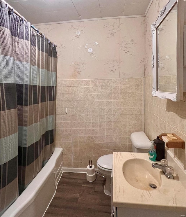 full bathroom featuring toilet, vanity, tile walls, hardwood / wood-style flooring, and shower / tub combo with curtain