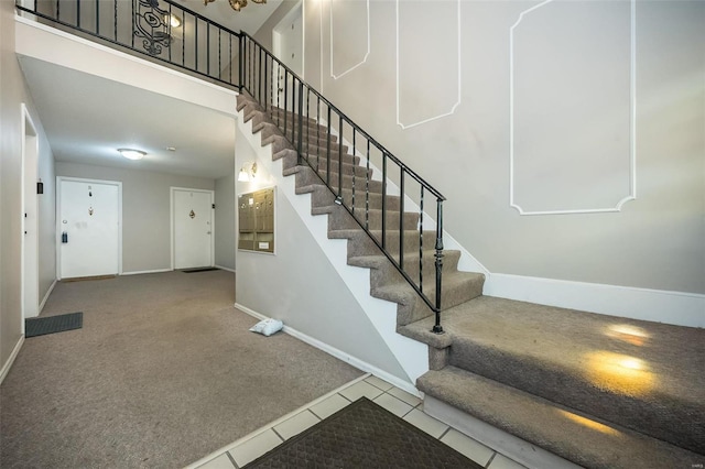 staircase featuring a high ceiling and tile patterned flooring