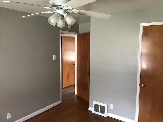 unfurnished bedroom featuring baseboards, a ceiling fan, visible vents, and dark wood-style flooring