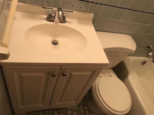 bathroom featuring tile walls, vanity, a tub, and toilet