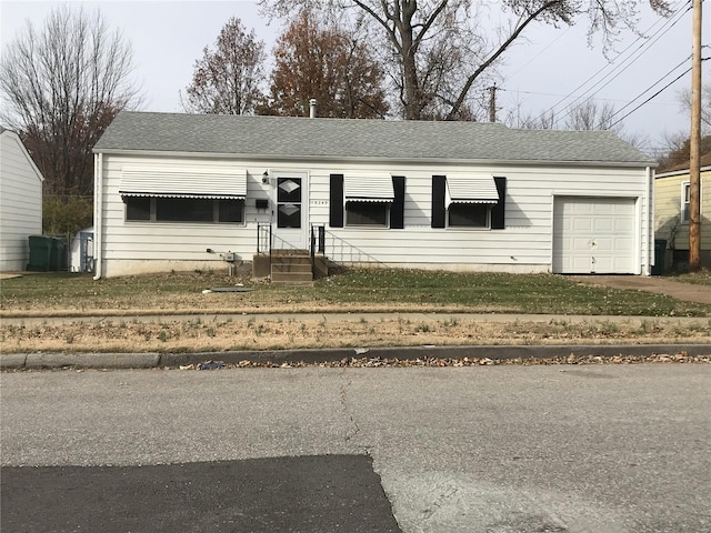 view of front of home featuring an attached garage, driveway, roof with shingles, and a front yard