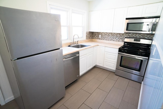 kitchen with backsplash, stainless steel appliances, white cabinets, and a sink