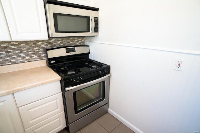 kitchen featuring white cabinetry, stainless steel appliances, decorative backsplash, and light tile patterned floors