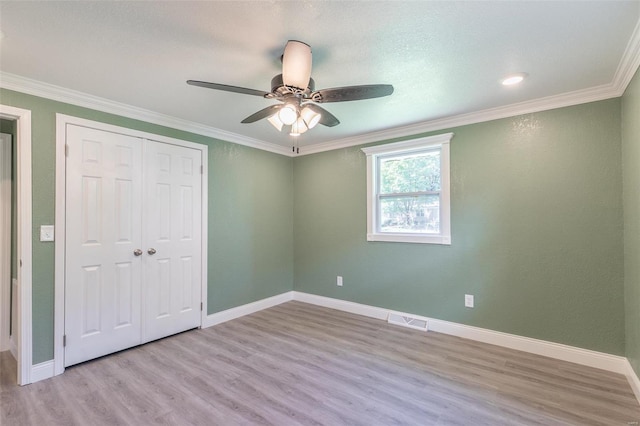 unfurnished bedroom with light hardwood / wood-style floors, ornamental molding, ceiling fan, and a closet