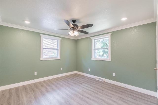 empty room featuring ornamental molding, light wood-type flooring, ceiling fan, and a healthy amount of sunlight