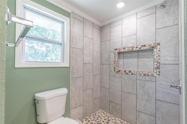 bathroom featuring a tile shower, crown molding, and toilet