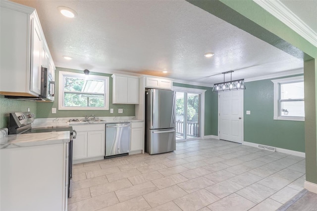 kitchen featuring stainless steel appliances, white cabinetry, a textured ceiling, and crown molding