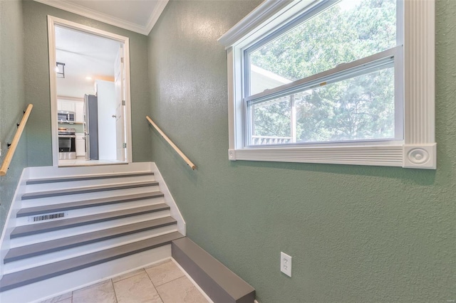 stairway featuring crown molding and tile patterned floors