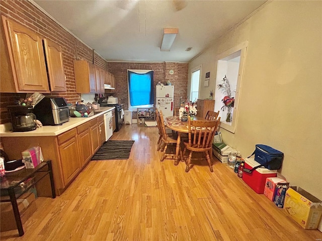 kitchen with stove, light hardwood / wood-style flooring, brick wall, and white refrigerator