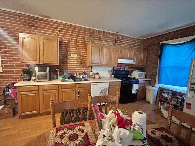 kitchen featuring sink, white appliances, light hardwood / wood-style flooring, and brick wall