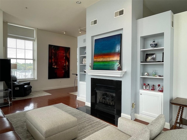 living room with built in features and dark hardwood / wood-style flooring