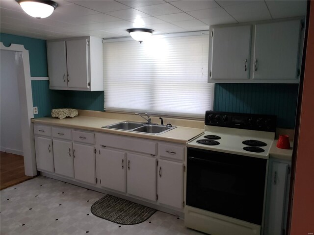 kitchen featuring light tile patterned floors, sink, electric stove, and white cabinets