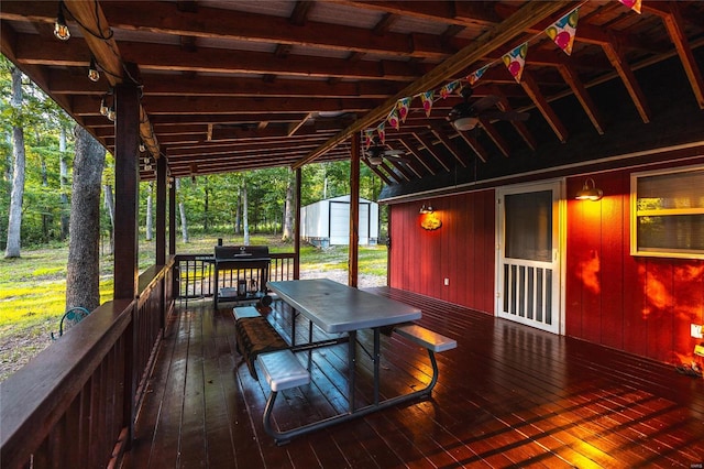 wooden terrace featuring ceiling fan and a shed