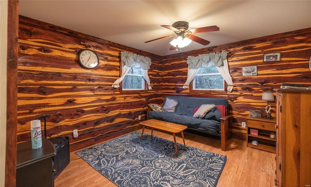 living room featuring ceiling fan, light hardwood / wood-style floors, and log walls