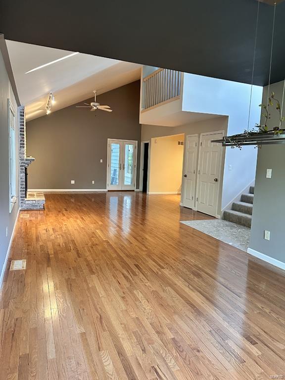 unfurnished living room with hardwood / wood-style flooring, ceiling fan, and high vaulted ceiling