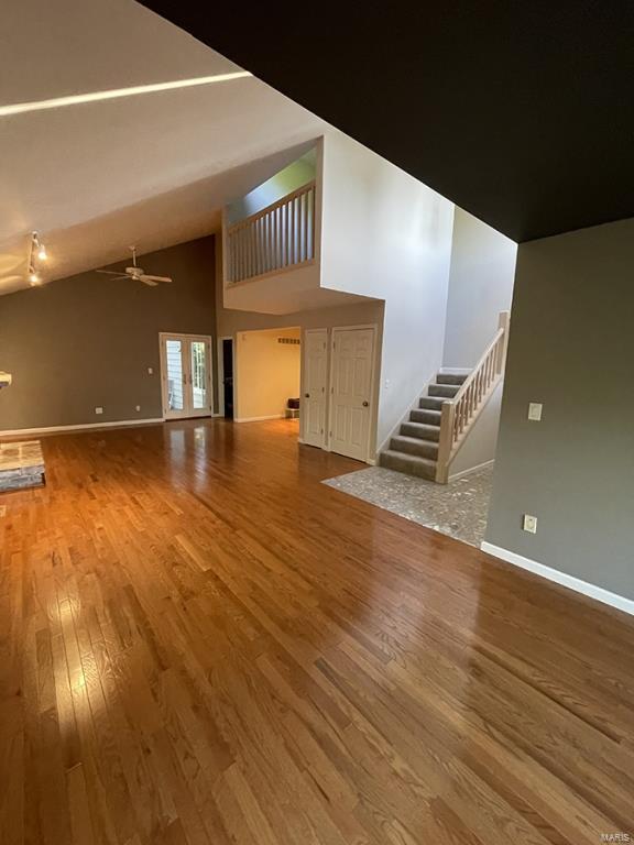 unfurnished living room with high vaulted ceiling, hardwood / wood-style floors, and ceiling fan