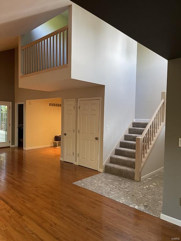 stairs featuring a high ceiling and hardwood / wood-style flooring