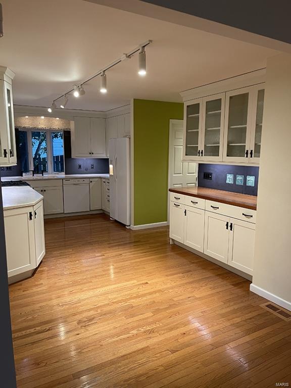 kitchen featuring track lighting, sink, white fridge with ice dispenser, white cabinetry, and light wood-type flooring