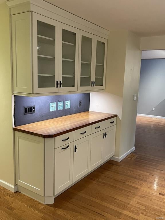 bar featuring white cabinets, light hardwood / wood-style floors, butcher block counters, and tasteful backsplash