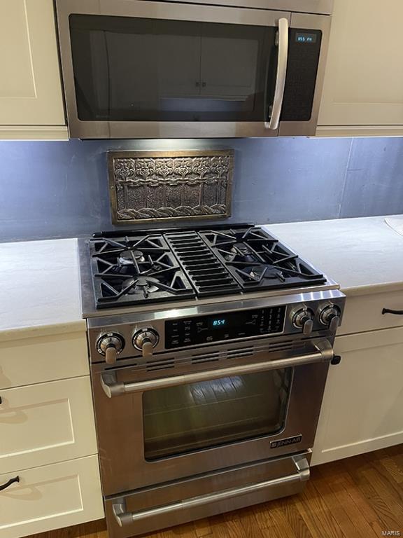 kitchen with white cabinetry, appliances with stainless steel finishes, and dark hardwood / wood-style floors