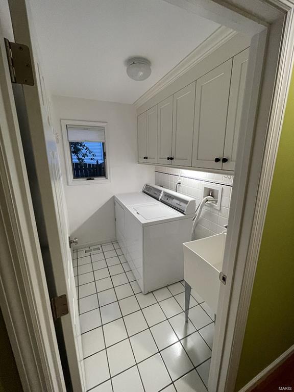 clothes washing area with cabinets, separate washer and dryer, light tile patterned floors, and crown molding