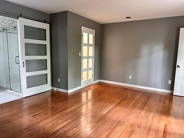 unfurnished room featuring hardwood / wood-style floors and a barn door