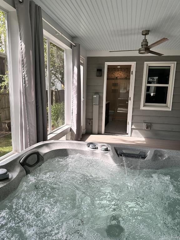 exterior space featuring ceiling fan, a healthy amount of sunlight, and a hot tub