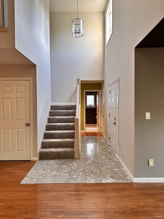 entrance foyer with a towering ceiling, wood-type flooring, and an inviting chandelier