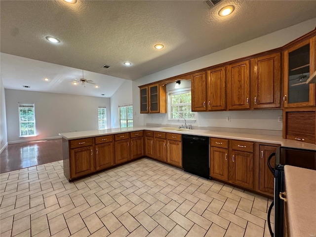 kitchen featuring dishwasher, ceiling fan, light tile patterned floors, kitchen peninsula, and vaulted ceiling